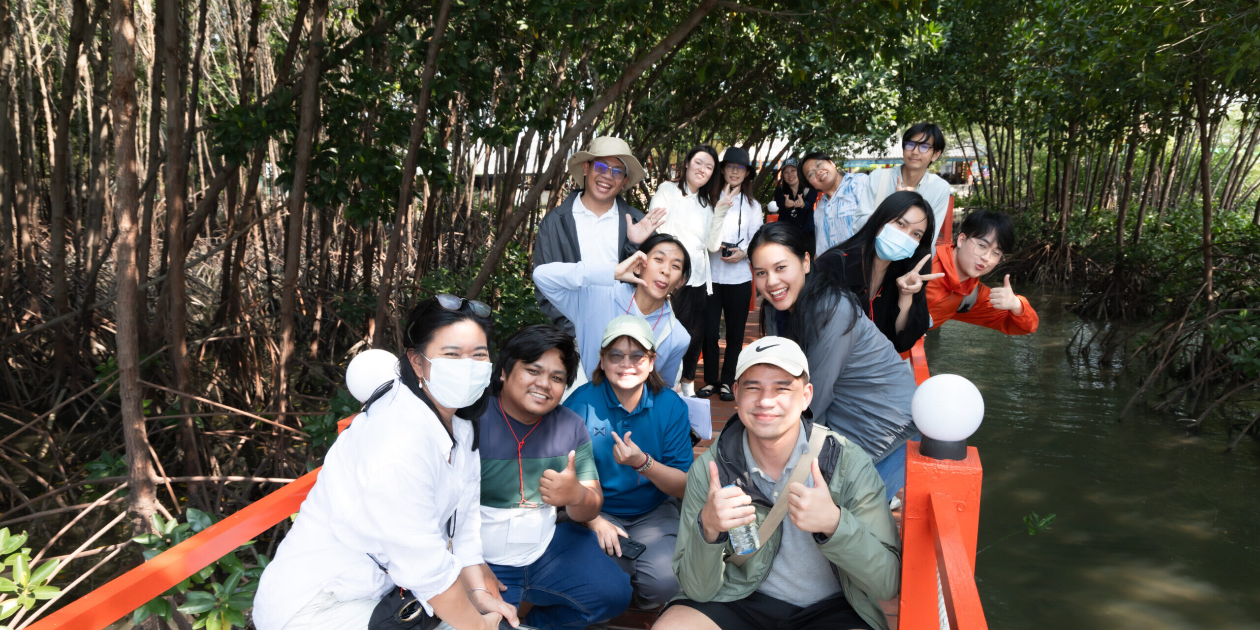 Participants of blue carbon workshop posing on a boardwalk among mangroves
